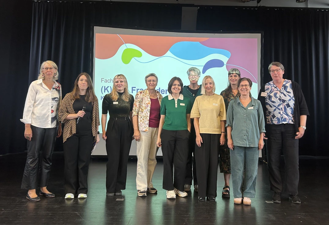 10 Frauen stehen in einer Gruppe auf einer Bühne: Gruppenbild der Referentinnen und Organisatorinnen